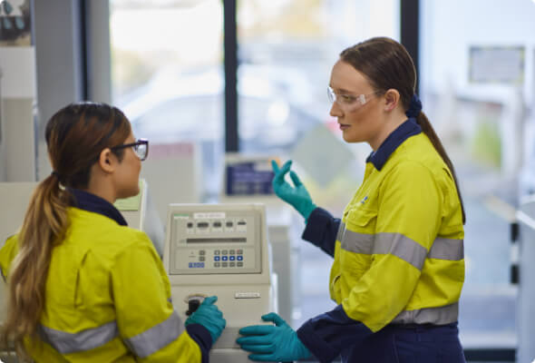 Two BlueScope employees in conversation over testing equipment in a laboratory 